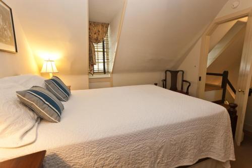 a bedroom with a large white bed with pillows at Colonial Houses, an official Colonial Williamsburg Hotel in Williamsburg