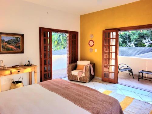 a bedroom with a bed and a chair and sliding doors at A Casa do Sol Ilhabela in Ilhabela
