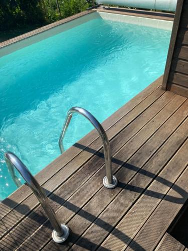 a swimming pool with a wooden deck next to a swimming pool at CHALET LOU PADER in Vézac