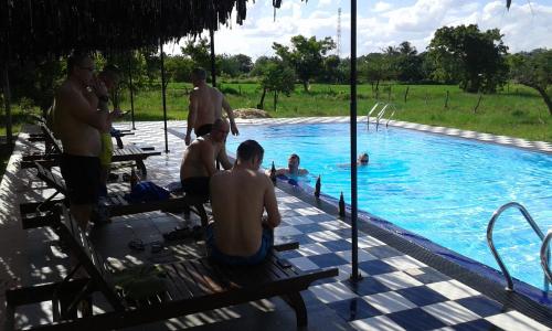 a group of men sitting around a swimming pool at Eco Hotel Black & White - Anuradhapura in Mihintale