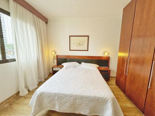 a bedroom with a white bed and a wooden cabinet at ENB | Flat hotel em SBC p/ 2 pp Espaço e Conforto in São Bernardo do Campo