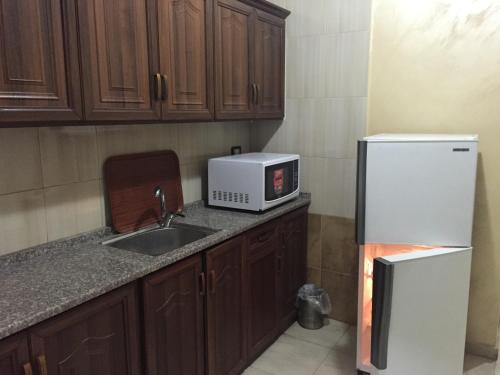 a kitchen with a sink and a microwave and a refrigerator at Al Tawheed Hotel Apartments in Amman