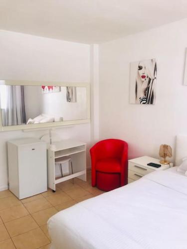 - une chambre blanche avec une chaise rouge et un bureau dans l'établissement logement tout proche de la plage, à Cannes