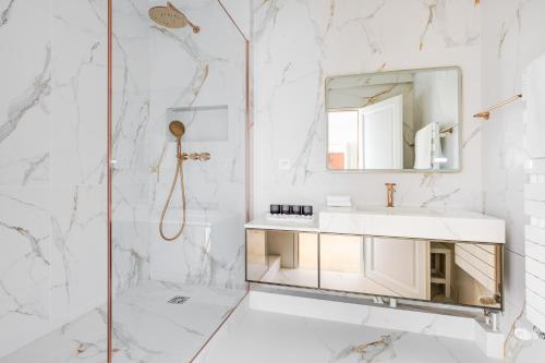 une salle de bain blanche avec un lavabo et un miroir dans l'établissement 101 Penthouse Royal à Paris avec Vue Imprenable sur la Tour Eiffel, à Paris