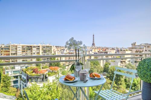 une table avec deux assiettes de nourriture sur un balcon dans l'établissement 101 Penthouse Royal à Paris avec Vue Imprenable sur la Tour Eiffel, à Paris