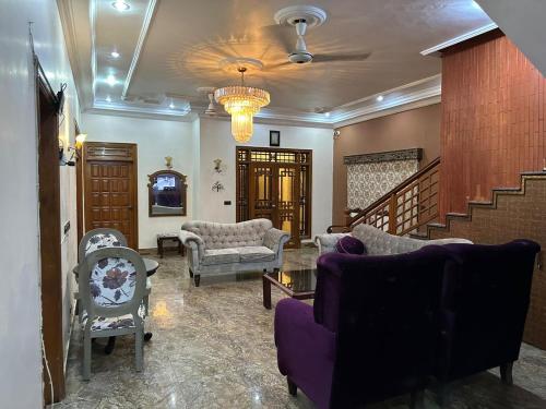 a living room with couches and chairs and a staircase at The Red Tree Family Guest House in Karachi