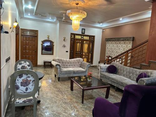 a living room with couches and chairs and a chandelier at The Red Tree Family Guest House in Karachi
