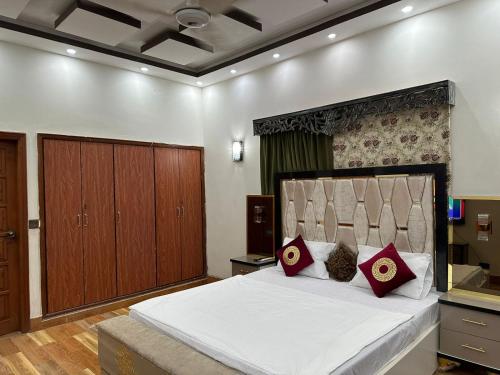a bedroom with a large white bed with red pillows at The Red Tree Family Guest House in Karachi