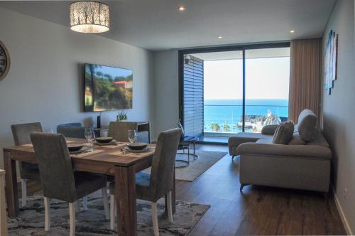 a living room with a dining table and a view of the ocean at Enchanted Bay in Câmara de Lobos