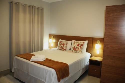 a bedroom with a large white bed with two pillows at Hotel Portal do Descobrimento in Porto Seguro