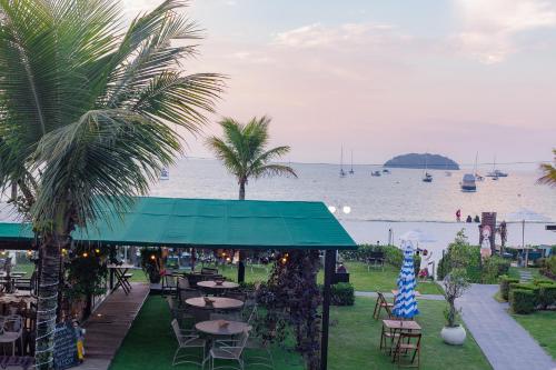 a restaurant with tables and palm trees next to the water at Hotel Sete Ilhas in Florianópolis
