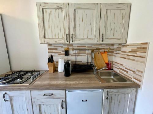 a kitchen with white cabinets and a sink at Júlia Apartmanház Harkány in Harkány