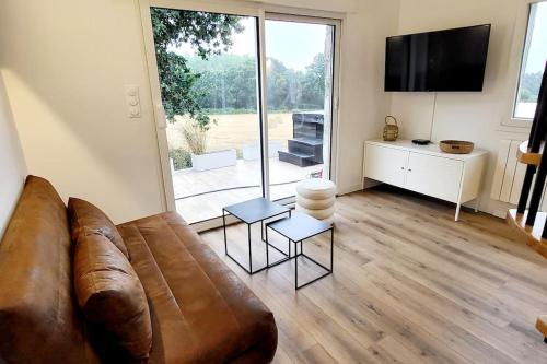 a living room with a brown leather couch and a large window at Parenthèse du Gouët Jacuzzi privatif Petit déjeuner in Ploufragan
