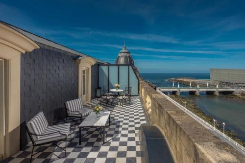 a balcony with chairs and a table and a view of the ocean at Hotel Maria Cristina, a Luxury Collection Hotel, San Sebastian in Donostia-San Sebastián