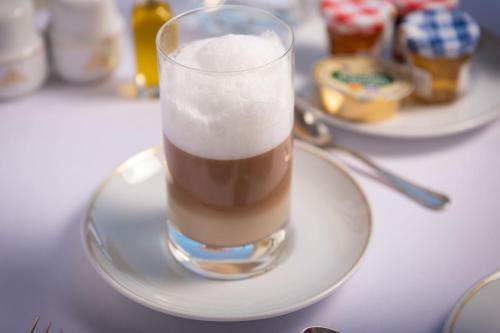 a glass of drink on a plate on a table at Hotel Maria Cristina, a Luxury Collection Hotel, San Sebastian in Donostia-San Sebastián