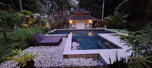 a swimming pool in a garden with a gazebo at Mi Casa - The gem of Ijen in Banyuwangi