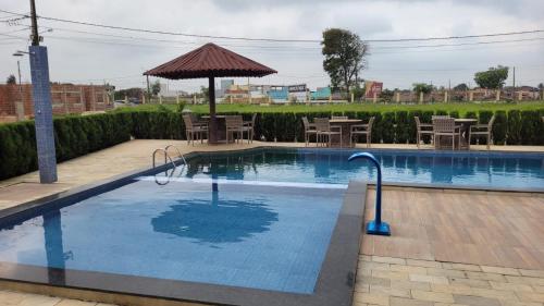 a swimming pool with an umbrella and tables and chairs at Casa espaçosa churrasqueira Wi-Fi há 2km do centro in Bananeiras