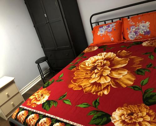 a bed with a red blanket with flowers on it at SHAY-BASEMENT-Holiday Home in Pickering