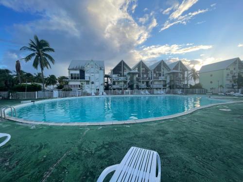 uma piscina com um banco branco em frente a alguns edifícios em Studio spacieux en bord de mer Bas du Fort Gosier em Le Gosier