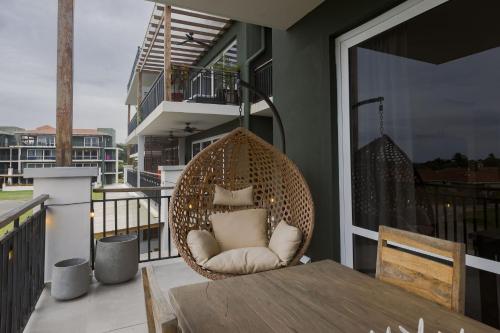 a wicker swing chair on a balcony with a table at Casa Palma Home at Blue Venao in Playa Venao