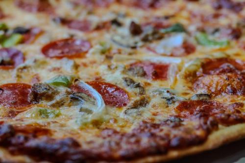 a pizza with pepperoni and vegetables on a table at Holiday Inn Quincy by IHG in Quincy