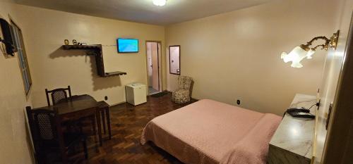 a bedroom with a bed and a desk and a television at Hotel Colonial in São João del Rei