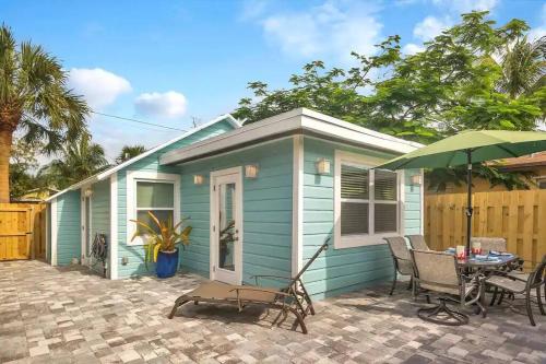 ein blaues Haus mit Tisch, Stühlen und einem Sonnenschirm in der Unterkunft Coastal Cottage - Just 7 Minutes to the Beach and Downtown! in Lake Worth