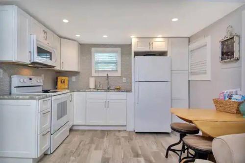 eine Küche mit weißen Geräten und einem Holztisch in der Unterkunft Coastal Cottage - Just 7 Minutes to the Beach and Downtown! in Lake Worth