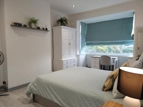 a bedroom with a bed and a desk and a window at Cozy Cottage - Close to London in Epsom