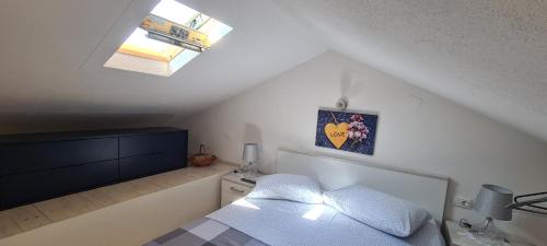 1 dormitorio en el ático con 1 cama y tragaluz en Studio apartman Loreta, en Cres