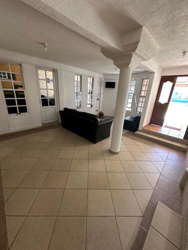 a living room with a black couch and a pillar at Casa acogedora in Tasquillo