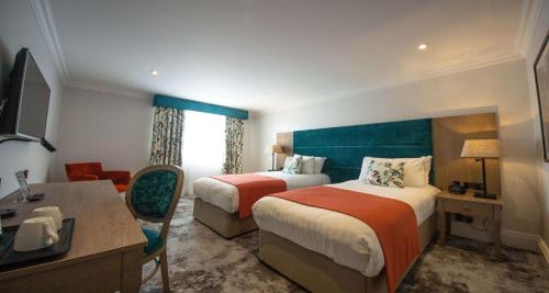 a hotel room with two beds and a desk at Best Western Abbots Barton Hotel in Canterbury