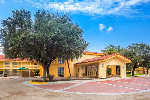 a yellow building with a tree in front of it at Super 8 by Wyndham Eagle Pass in Eagle Pass