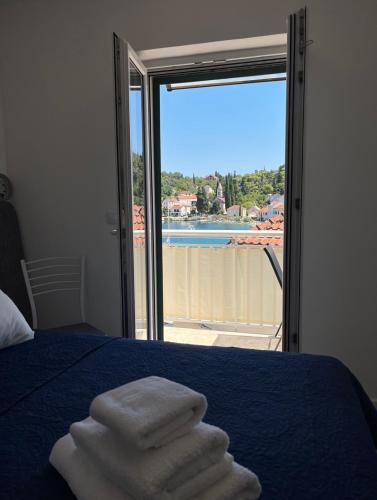 a pile of towels sitting on a bed with a window at Apartmani Antonia in Račišće