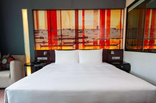 a bedroom with a large white bed and a painting at Park Plaza Bangkok Soi 18 in Bangkok
