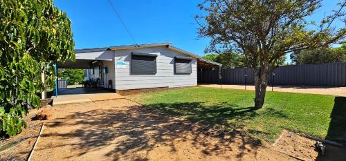 a white house with a tree in the yard at Patrick Crescent 18 - Kalbarri, WA in Kalbarri
