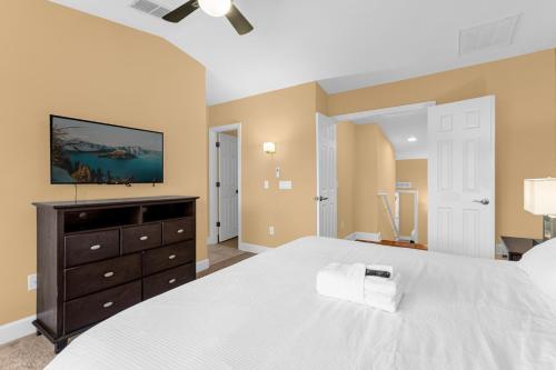 a bedroom with a large white bed and a dresser at 4BR Disney Family Townhouse Resort in Orlando - with Resort Pool, Gym, Games, & Jacuzzi in Orlando