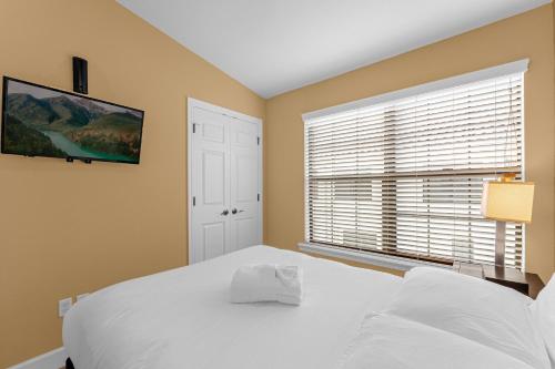 a bedroom with a white bed and a window at 4BR Disney Family Townhouse Resort in Orlando - with Resort Pool, Gym, Games, & Jacuzzi in Orlando