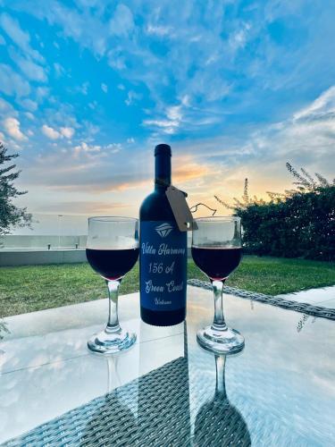 a bottle of wine and two glasses on a table at Villa Harmony Green Coast, Palase in Himare