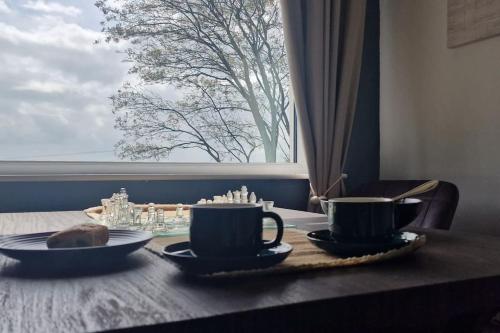 a table with two cups and plates on a table with a window at Bracken Cottage in Ballyeaston