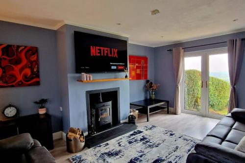 a living room with a television above a fireplace at Bracken Cottage in Ballyeaston