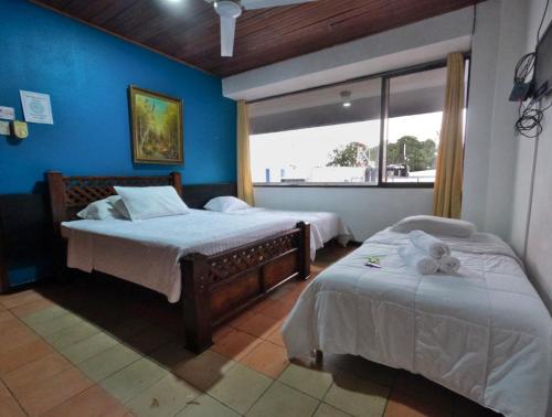 a bedroom with two beds and a large window at Hotel Alajuela Costa Rica Airport in Alajuela City