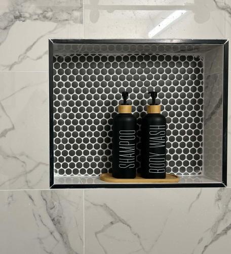two black bottles sitting on a shelf in a bathroom at DT Stylish & Newly Renovated Home 2BR Sea Tac 6 Miles with AC in Renton