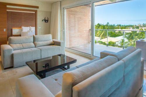 a living room with a couch and a large window at Hotel Tango Suítes Cumbuco in Cumbuco