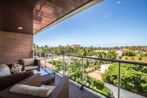 a balcony with a view of the ocean and palm trees at Hotel Tango Suítes Cumbuco in Cumbuco