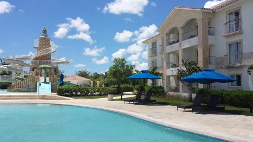 a swimming pool in front of a building with umbrellas at Cadaques Caribe Pez 103 in Bayahibe