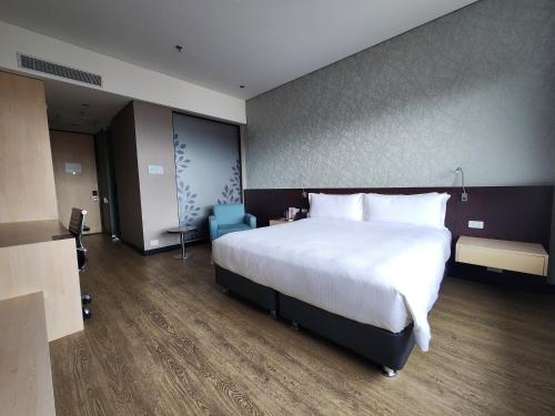 a bedroom with a large white bed and a blue chair at Hilton DoubleTree Bogotá Salitre AR in Bogotá