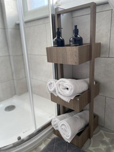 a bathroom with a towel rack with towels and a shower at Luton Airport House, Opposite airport staff parking in Luton