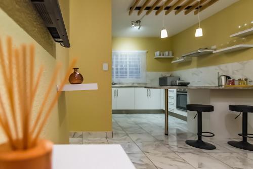 a kitchen with yellow walls and black stools at Azies - The Willows in Johannesburg