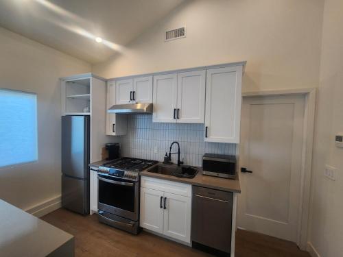 a kitchen with white cabinets and a stove and refrigerator at Ladera Retreat near Sofi Stadium, LAX, Beach in Los Angeles